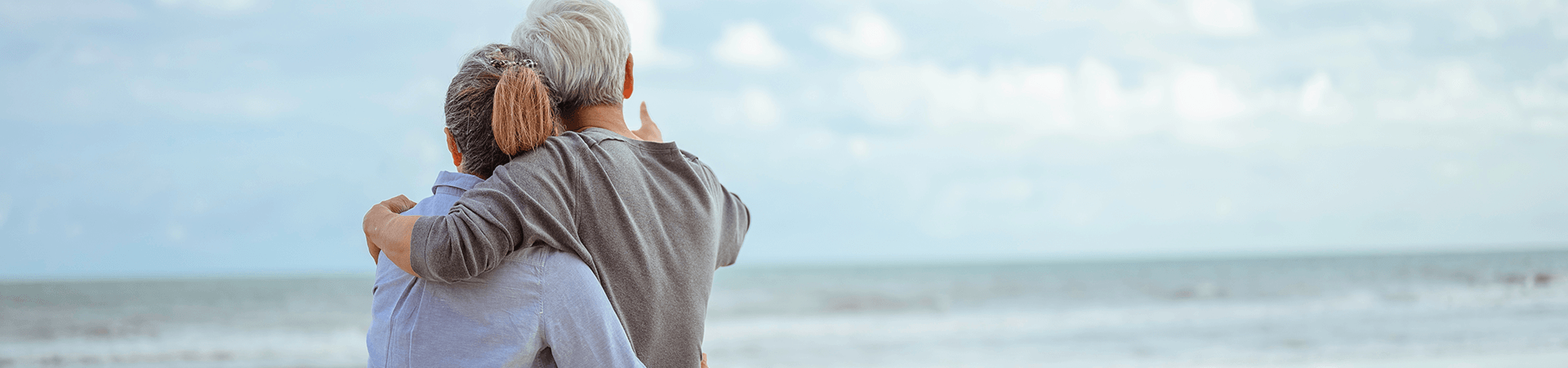 Un homme et une femme se prennent dans les bras en regardant la mer