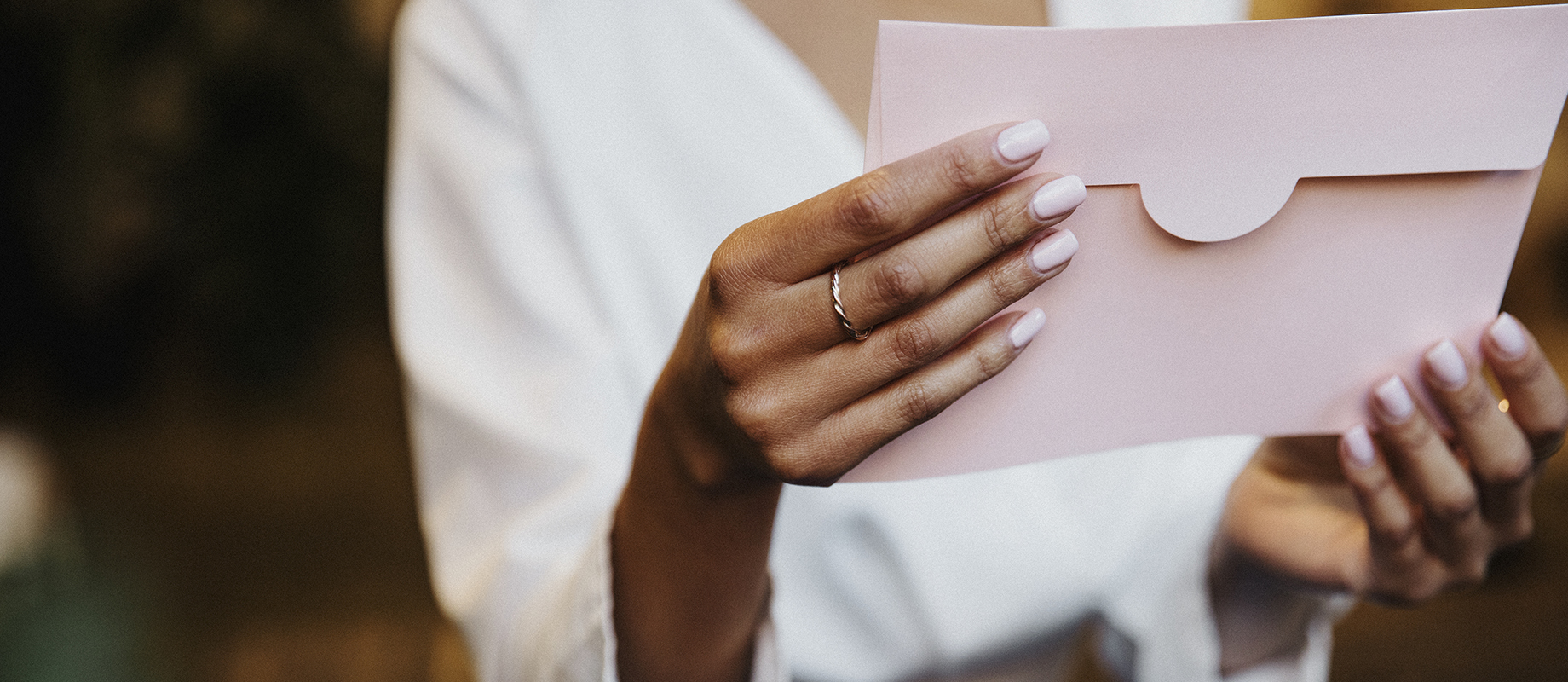 Une personne tient une enveloppe rose poudrée entre ses mains