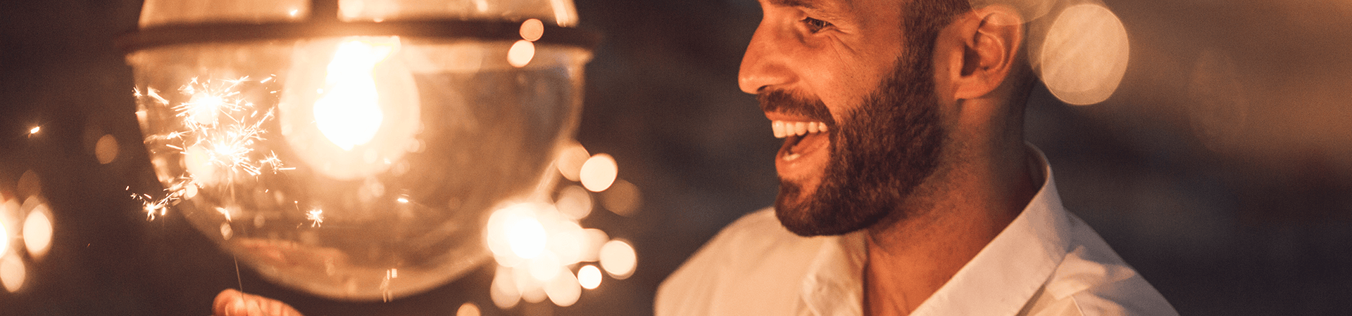 Un homme sourit en regardant les éteincelles de bougies