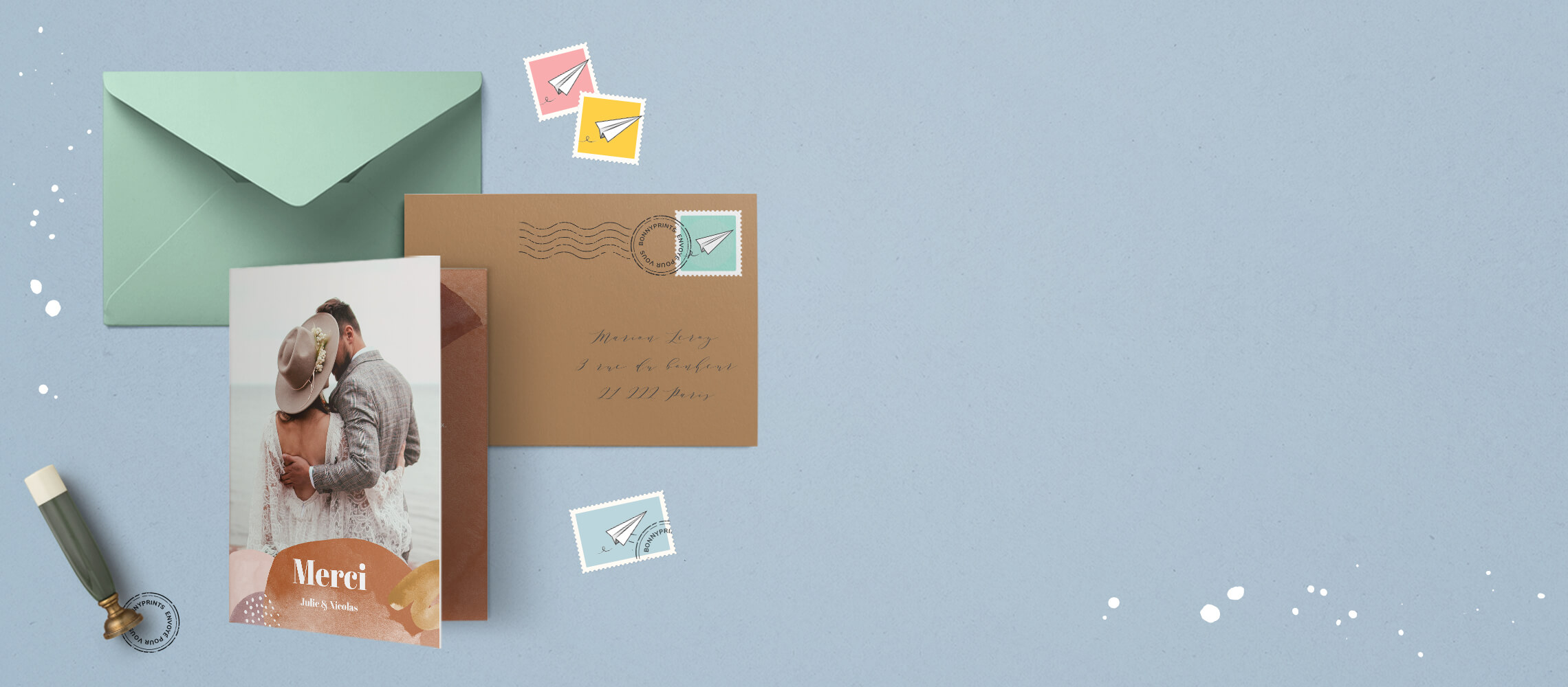 Une carte avec une enveloppe kraft, une enveloppe verte et des timbres sur fonc bleu clair